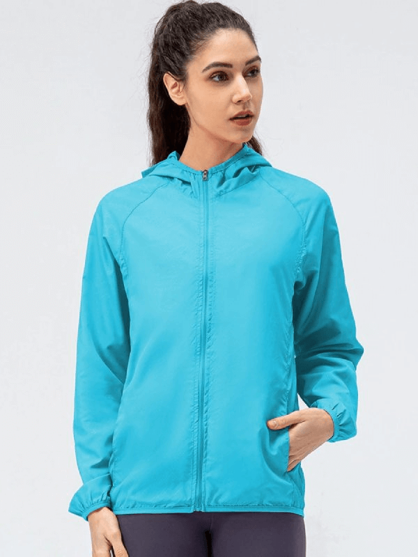 Sporty woman in turquoise waterproof windbreaker with hood, perfect for running outdoors. Stylish and functional outerwear.